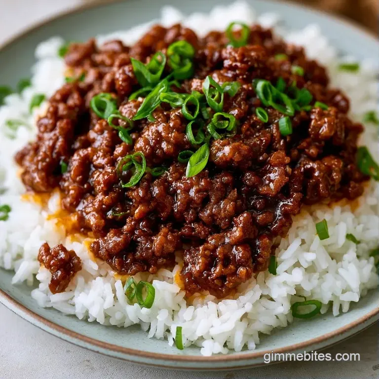 Brown glazed minced meat in a ceramic bowl topped with sesame seeds and thin curls of bright green scallions.